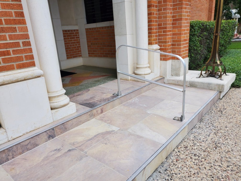 Finished commercial flooring at a public-facing entrance &mdash; precision-cut transitions, even joint reveals, and curb-quality alignment with adjacent masonry.